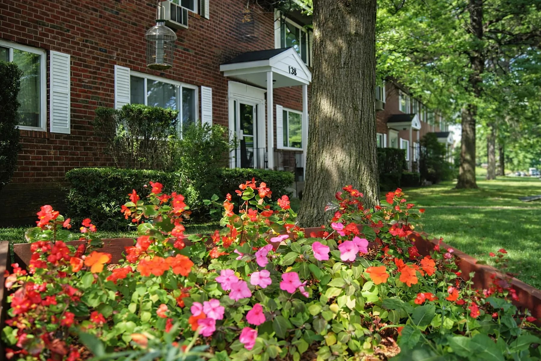 Harbour Point Gardens, Troy, NY: Red and pink flower bed at brick entry